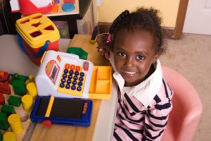 Little girl playing with cash register