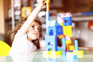 Little girl building a house with cubes